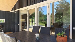 Un espace de restauration en plein air avec une table en bois foncé, des chaises en osier et une plante en pot.
