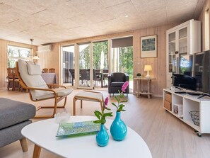 Ein modernes Wohnzimmer mit Sofa, Sesseln, Couchtisch und Fernseher.