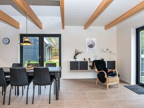 Un comedor moderno con una mesa, sillas y vistas al exterior a través de un ventanal.