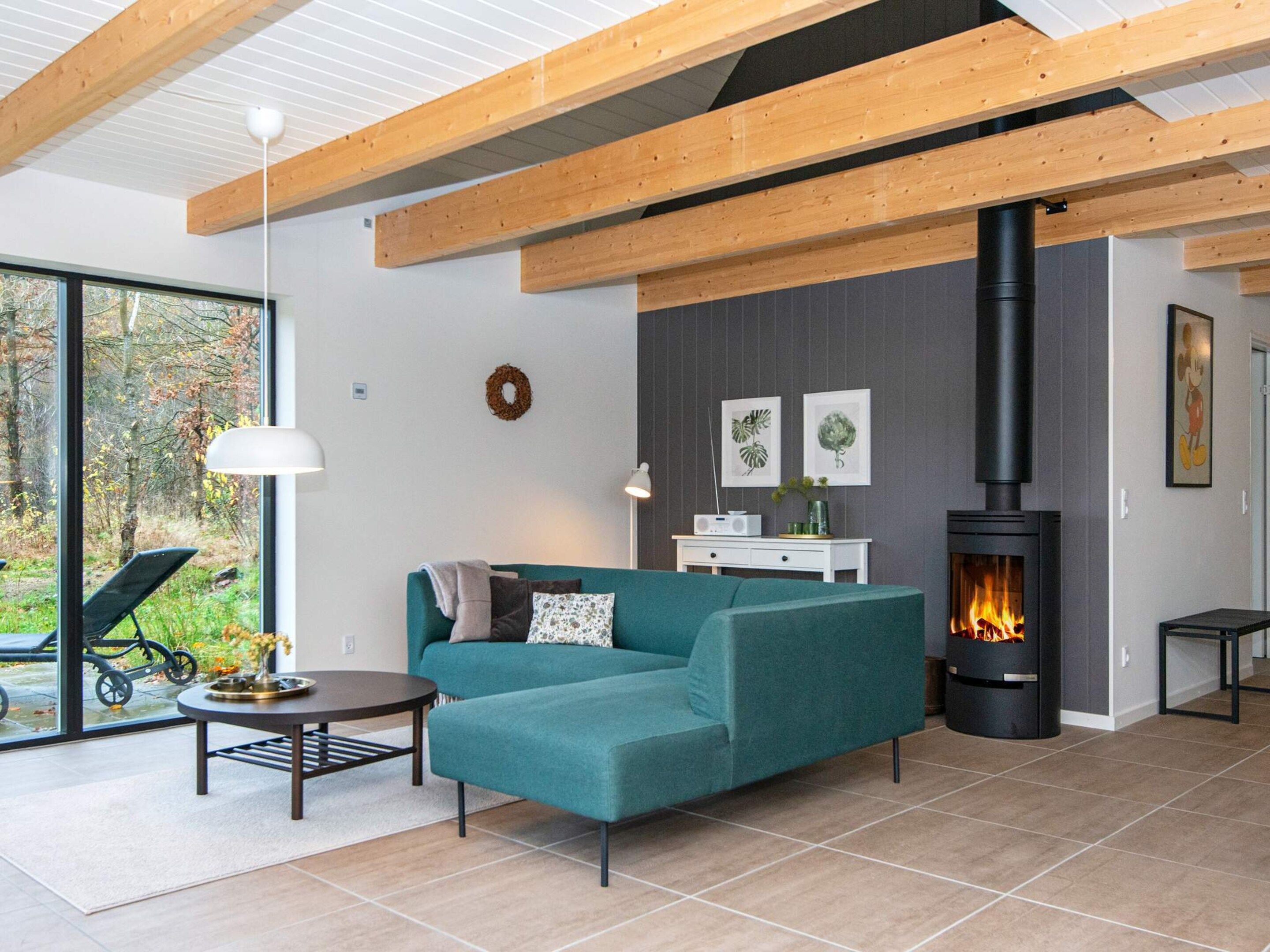 A modern living room with a sofa, a table, a fireplace, and a view of the outdoors.
