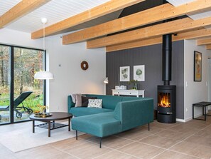 A modern living room with a sofa, a table, a fireplace, and a view of the outdoors.