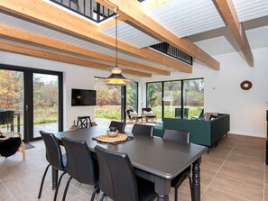 Een moderne eetruimte met een grote tafel, stoelen en een aan de muur bevestigde televisie.