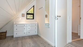 A room with a white vanity, a mirror, a window with a view, and a door leading to another room.