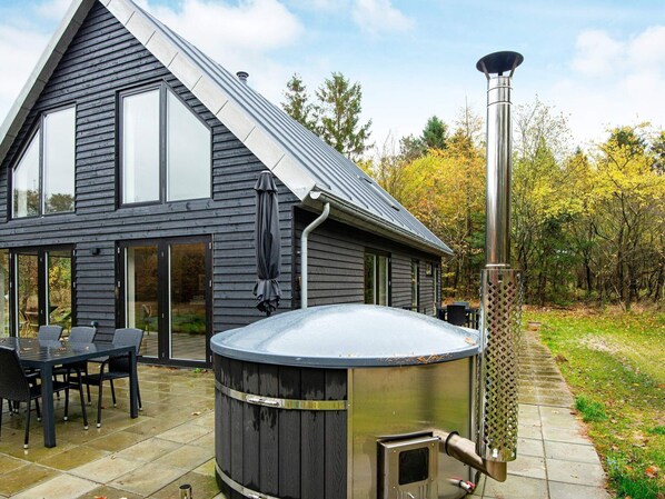 A modern house with a large hot tub and a chimney.
