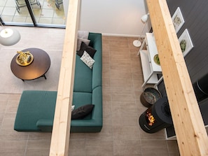 Un espacio habitable moderno con un sofá verde, una mesa redonda de centro y una chimenea.