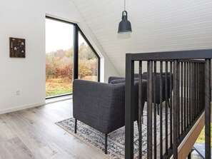 A modern interior with a large window, a dark sofa, and a hanging light fixture. - 6 Person Holiday Home in Hovborg (Hovborg)
