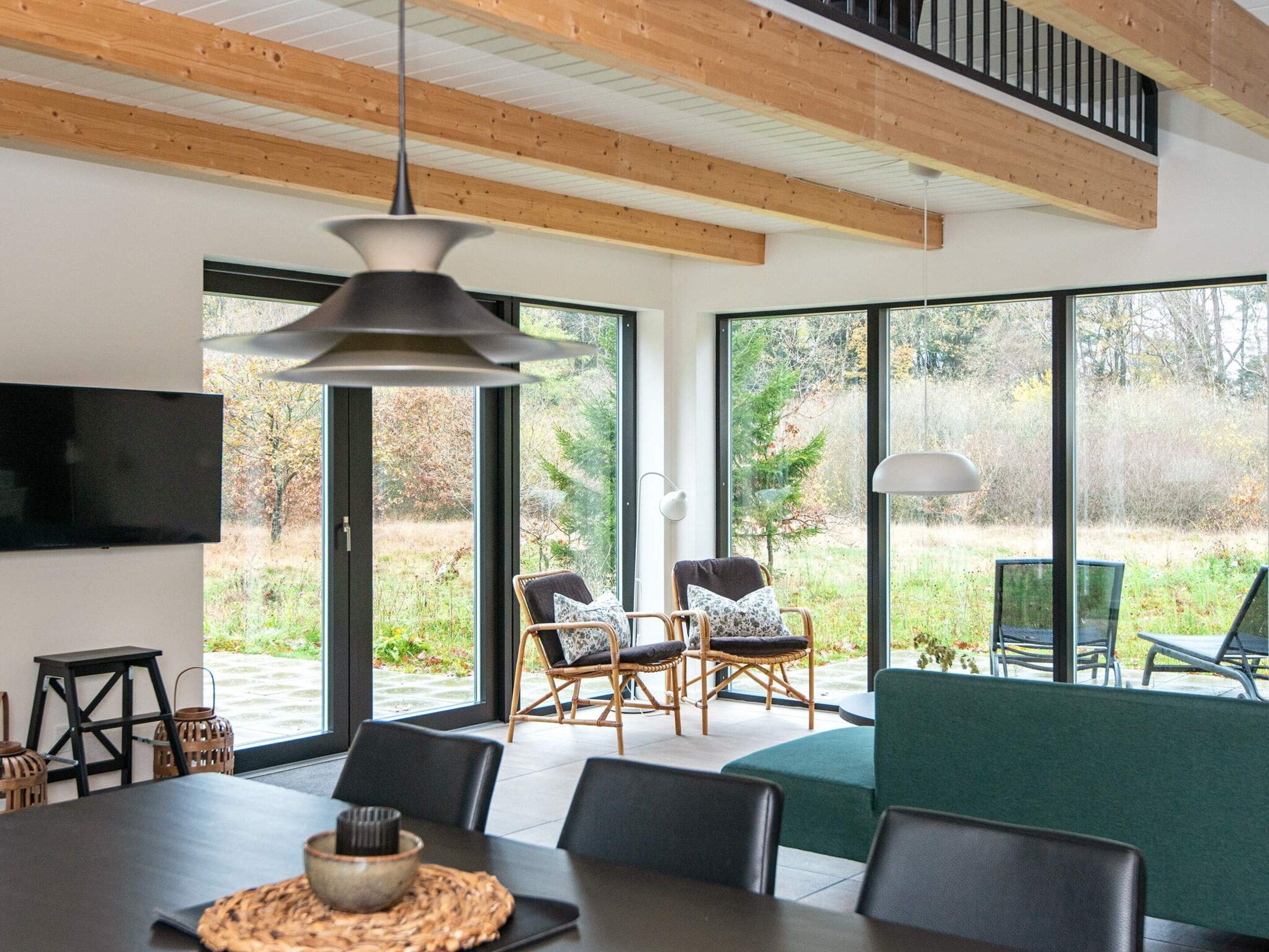A modern dining area with a large table, chairs, and a television on the wall.