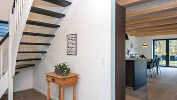 A staircase with dark railings, a wooden side table with a plant, and a framed picture on the wall.