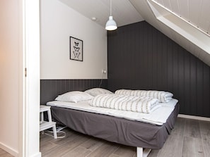 Un dormitorio con una cama, una mesita de noche, una lámpara colgante y un cuadro en la pared.