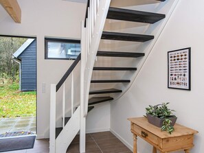 A modern interior with a spiral staircase, a framed fish collection, and a small wooden table with a plant.