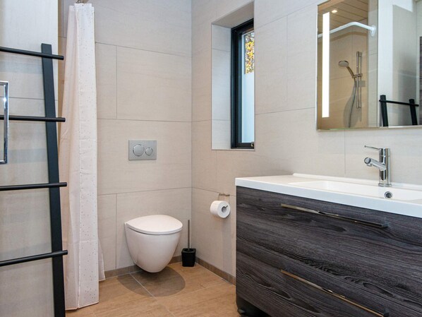 Un baño moderno con inodoro, lavamanos y ducha.