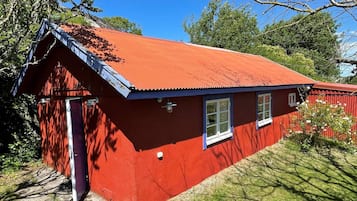A red wooden house with a sloped roof and a small porch.
