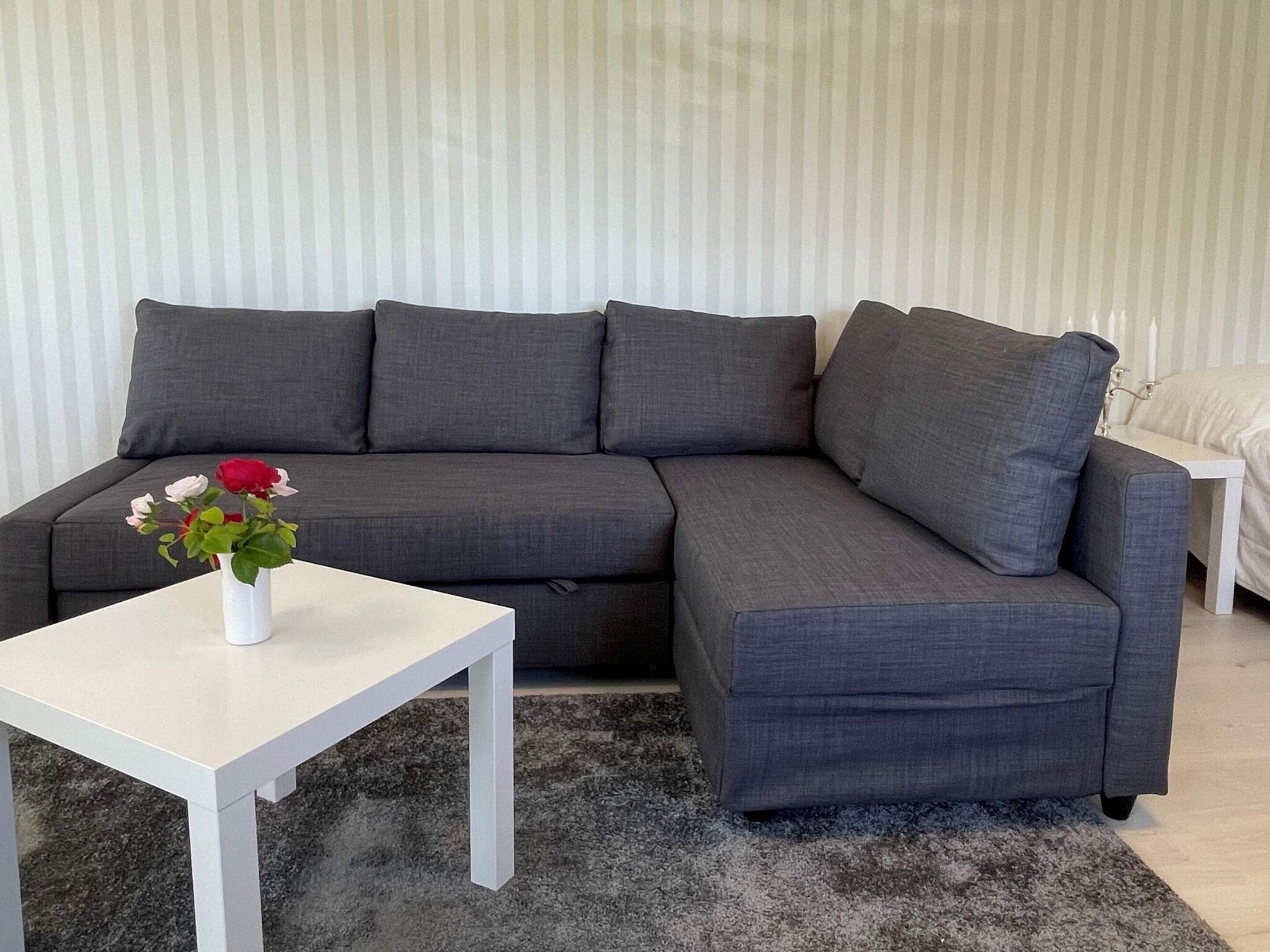 Un sofá seccional gris con una mesa de centro blanca.