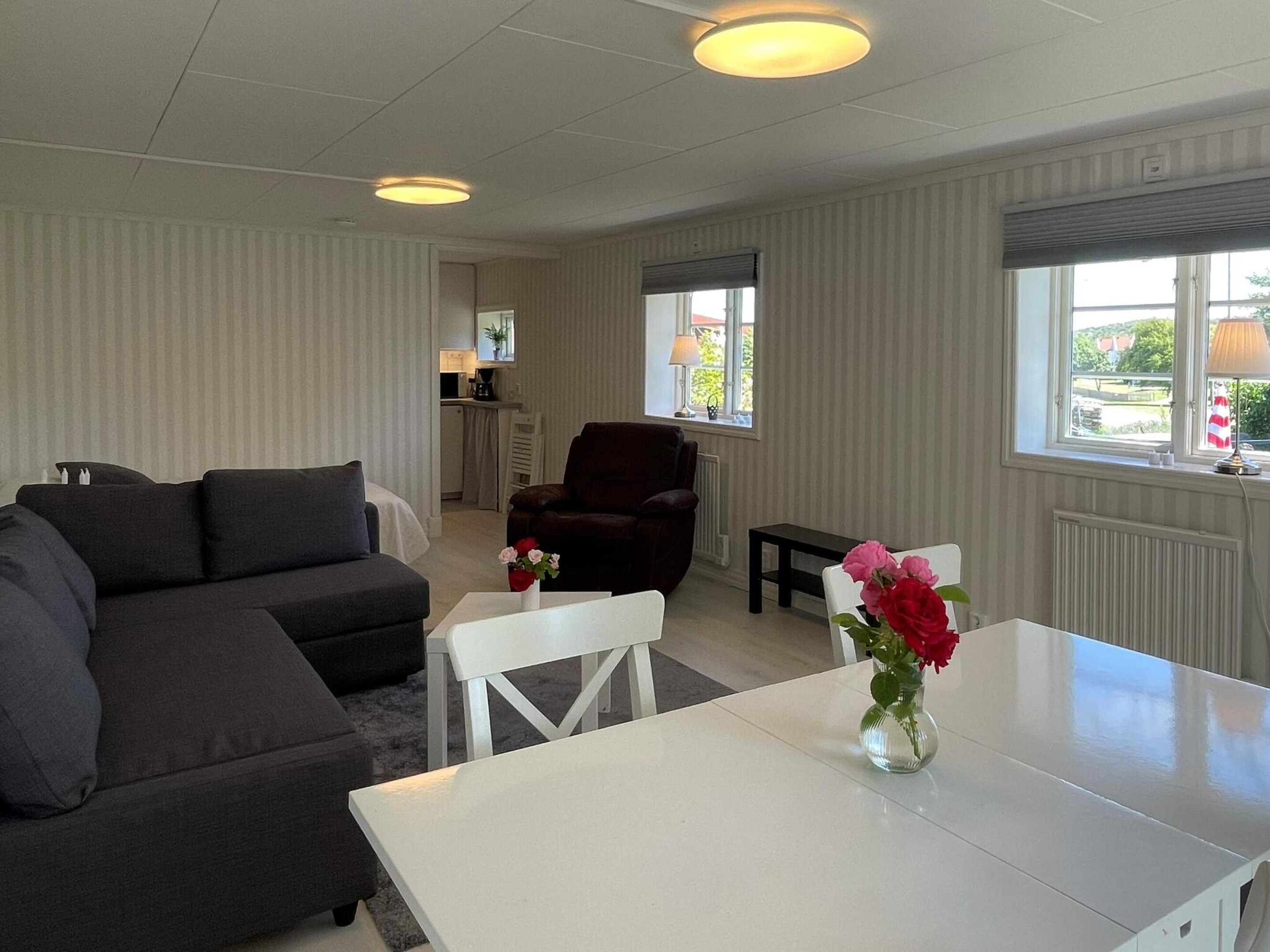 A modern living room with a sectional sofa, a dark armchair, a white table, and a vase of flowers.