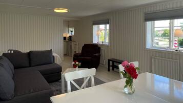 A modern living room with a sectional sofa, a dark armchair, a white table, and a vase of flowers.