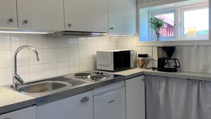 Eine Küche mit weißen Schränken, einer Edelstahl-Spüle, einer Mikrowelle und einer Kaffeemaschine.