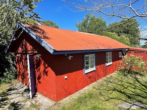 A red wooden house with a sloped roof, a small porch, and a window. - 4 Star Holiday Home in Skarhamn (Skaerhamn)