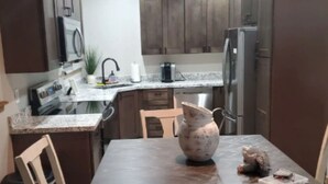 A modern kitchen with wooden cabinets, a granite countertop, and a dining table with chairs. - Beautiful Cabin in Unbeatable Location (Pinetop-Lakeside)