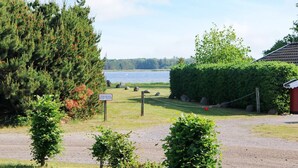A gravel path leading to a lake with a sign indicating a camping area. - 4 Person Holiday Home in Storvorde (Storvorde)