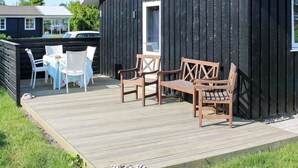 A wooden deck with outdoor furniture, a black building with a window, and a white fence. - 4 Person Holiday Home in Storvorde (Storvorde)