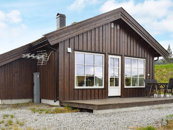 A wooden cabin with large windows and a covered outdoor seating area. - 7 Person Holiday Home in Nesbyen (Nes)