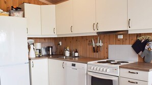 A compact kitchen with white cabinets, a stove, and a refrigerator.