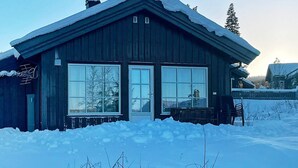 A wooden cabin with large windows and a snow-covered roof.