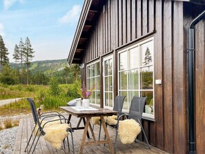A wooden cabin with a deck, large windows, and a table with chairs. - 7 Person Holiday Home in Nesbyen (Nes)