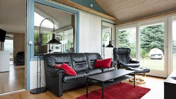 Uma sala de estar moderna com um sofá de couro preto, um tapete vermelho e piso de madeira.
