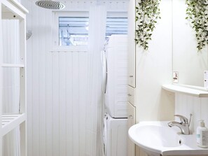 A compact bathroom with a white sink, a mirror, and a shower.
