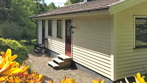 A single-story house with a front porch, a chimney, and a window overlooking a garden. - 4 Person Holiday Home in Dingle (Dingle)