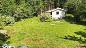 A grassy yard with a small white house, a table, and two chairs. - 4 Person Holiday Home in Dingle (Dingle)