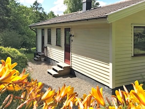 A single-story house with a front porch, a chimney, and a gravel driveway.
