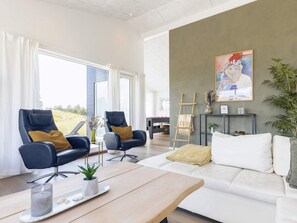 A modern living room with a sofa, two armchairs, a coffee table, and a painting on the wall. - 5 Star Holiday Home in Oksbol (Oksbol)
