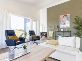 Una sala de estar moderna con un sofá, dos sillones, una mesa de centro y un cuadro en la pared.
