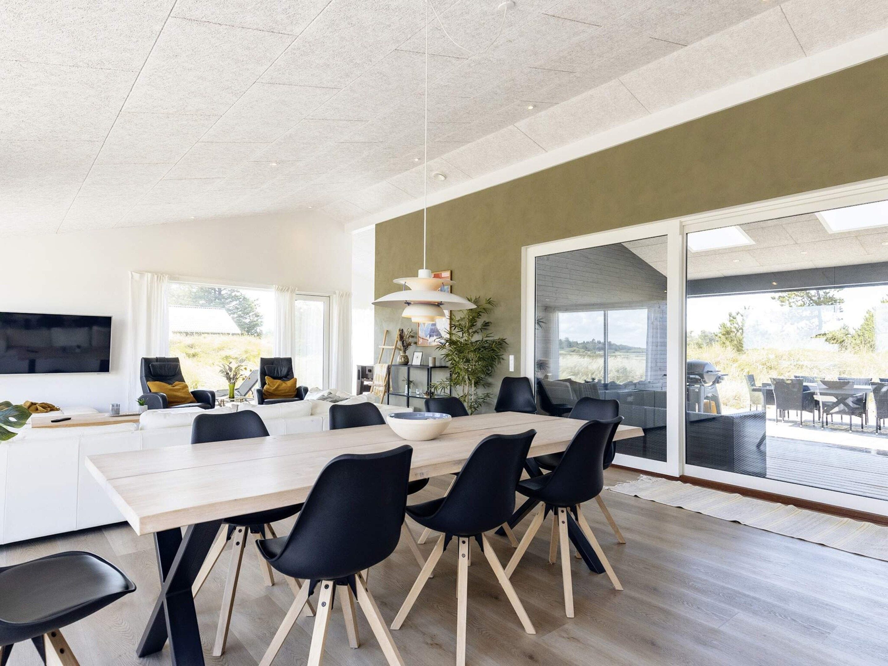 Un comedor moderno con una mesa larga, sillas negras y un gran ventanal con vistas al exterior.