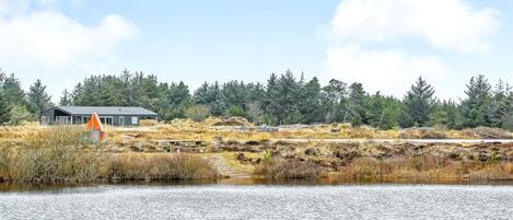 A lakeside view with a building, a picnic table, and surrounding vegetation.