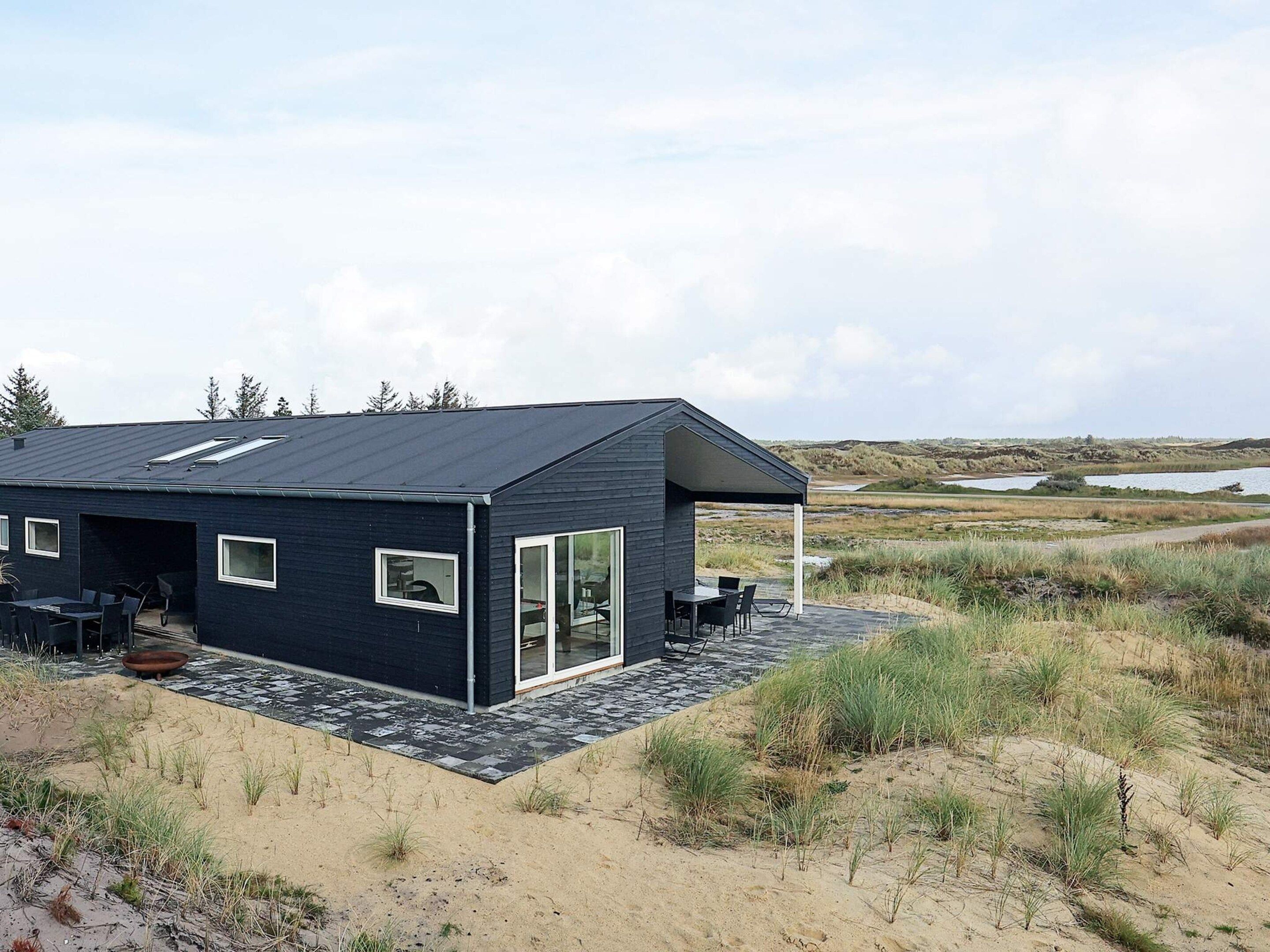 Una casa moderna con techo plano, ventanas amplias y un patio.