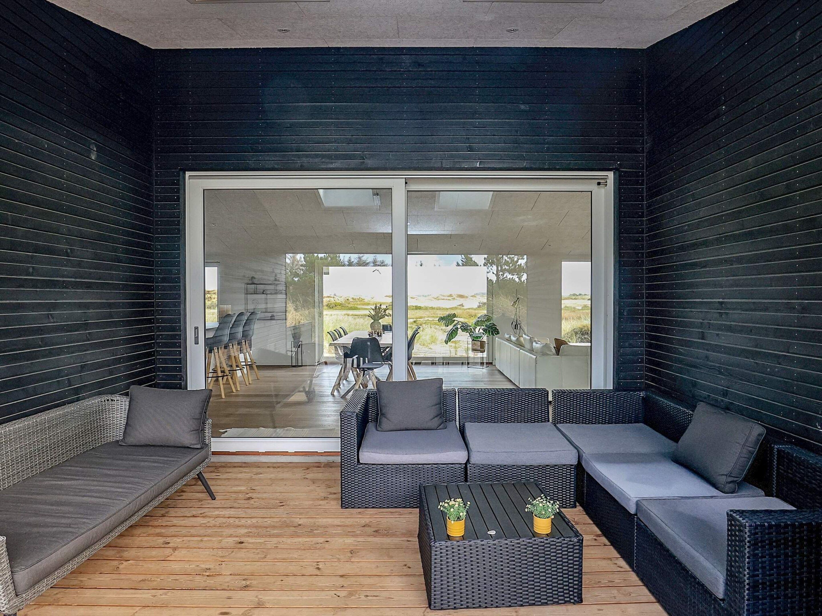 A modern outdoor living space with a sofa, chairs, and a coffee table.