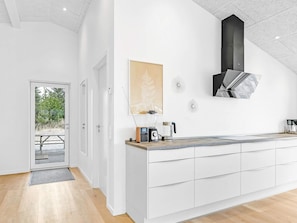 Een moderne keuken met witte kasten, een houten aanrechtblad en een zwarte afzuigkap.