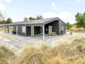 Een modern gebouw met een plat dak, grote ramen en een overdekte patio.
