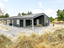 A modern building with a flat roof, large windows, and a covered patio area.
