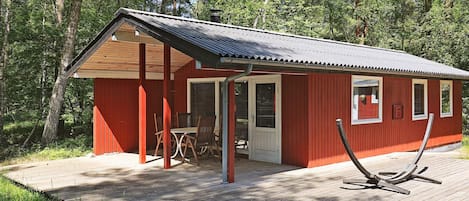 A red cabin with a covered patio, a door, and a window.