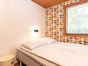 A bedroom with a bed, a bedside table, a wall-mounted light, and a window with blinds. - 5 Person Holiday Home in Stege (Stege)