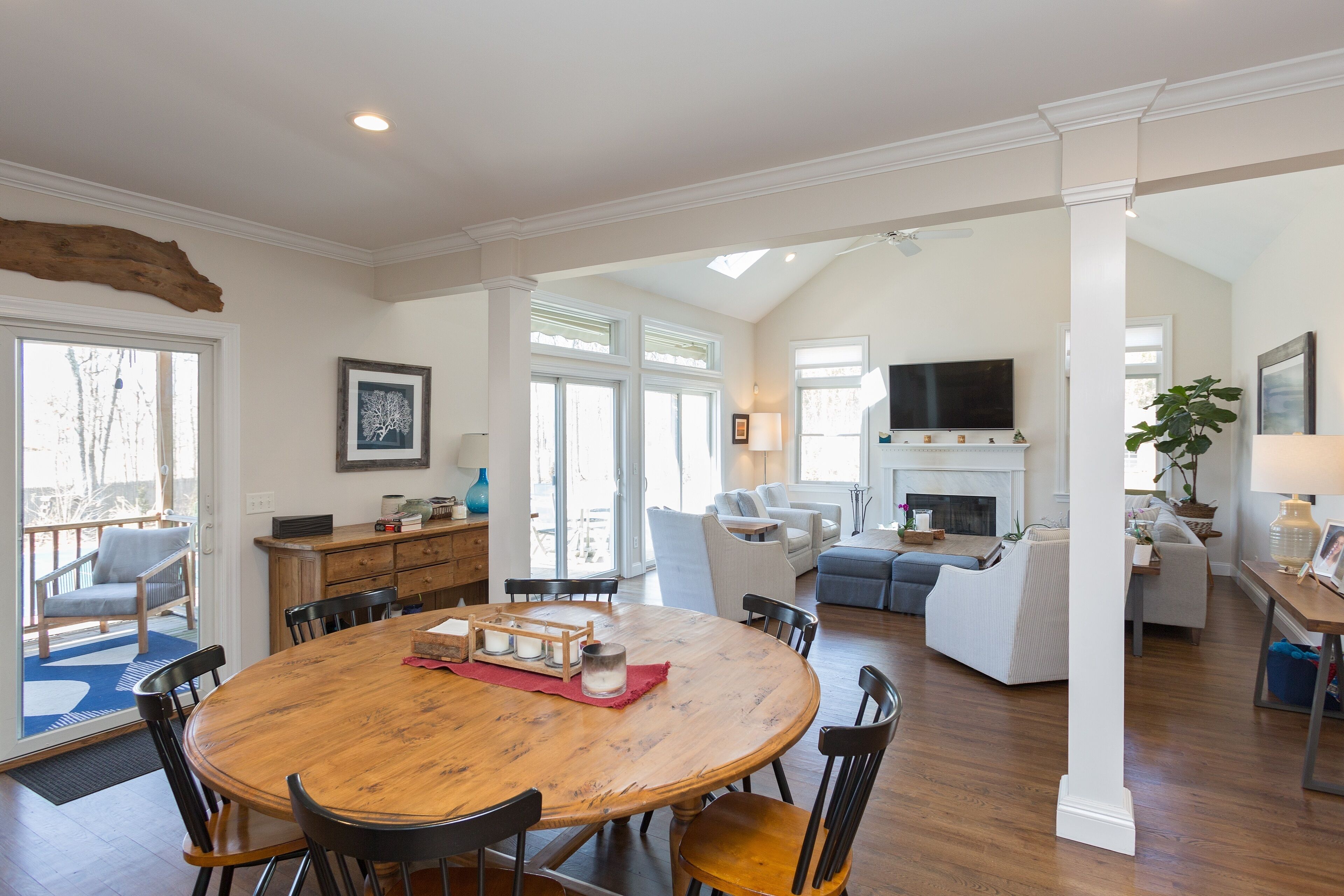 A spacious living room with a wooden dining table, comfortable seating, a fireplace, and a TV.