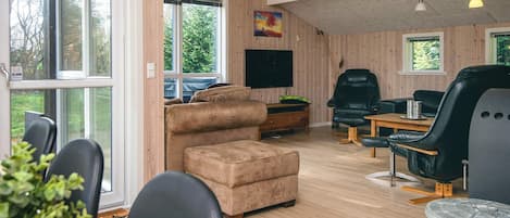 Una sala moderna con sofá, sillas, televisor y comedor.