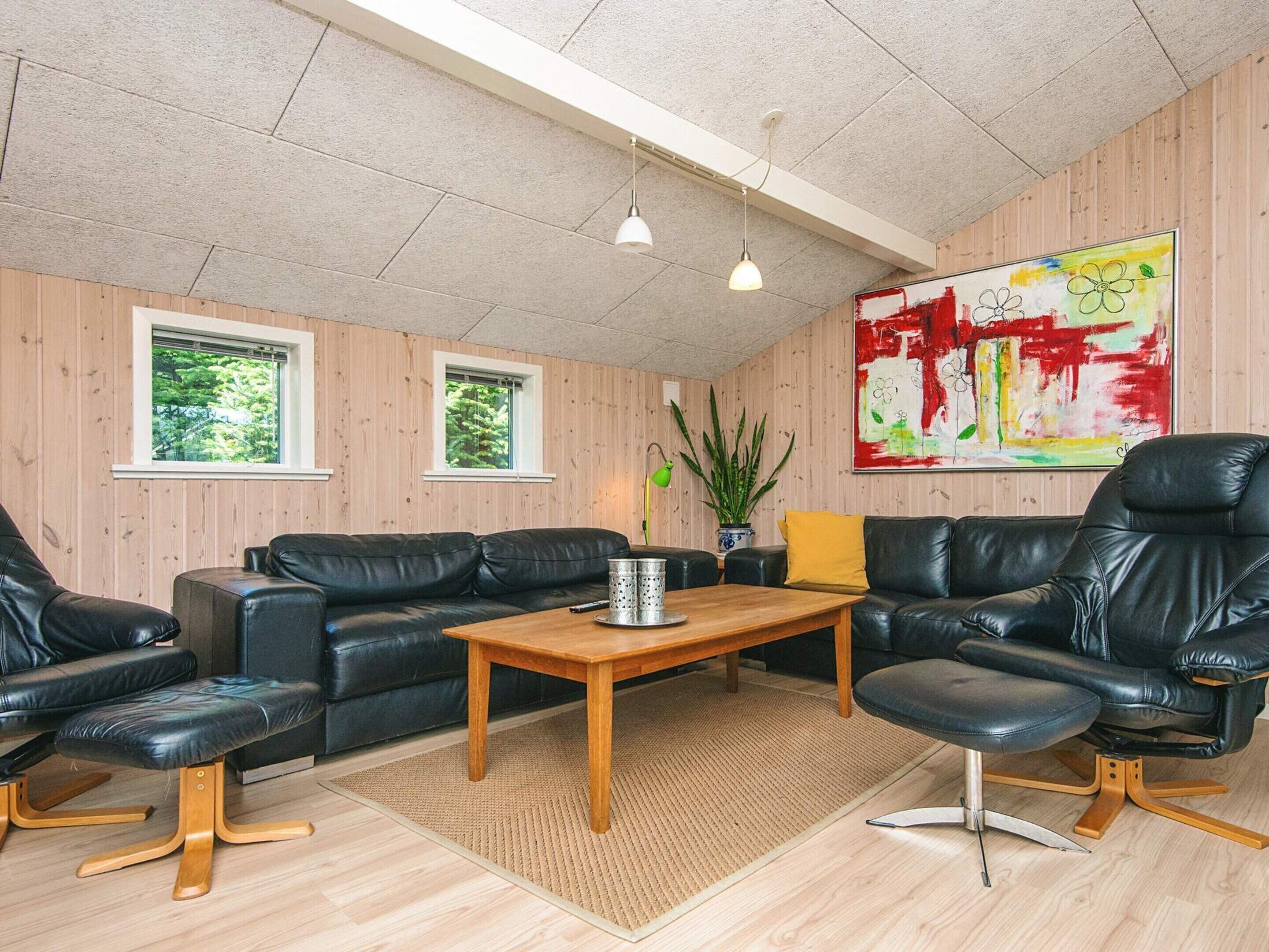 A modern living room with leather sofas, a wooden coffee table, and a large abstract painting on the wall.