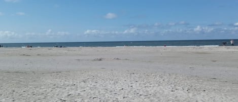 A beach with a wide sandy area and the ocean in the background.