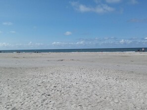 Uma praia com uma extensa área de areia e o oceano ao fundo.