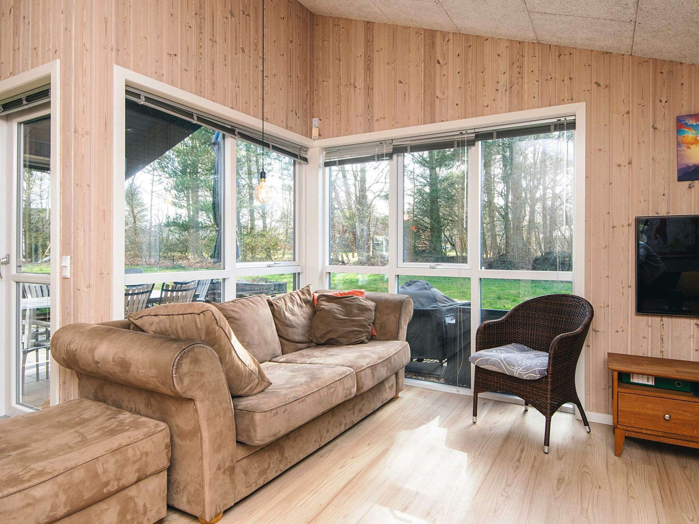 A room with a large window, a sofa, a chair, and a TV.
